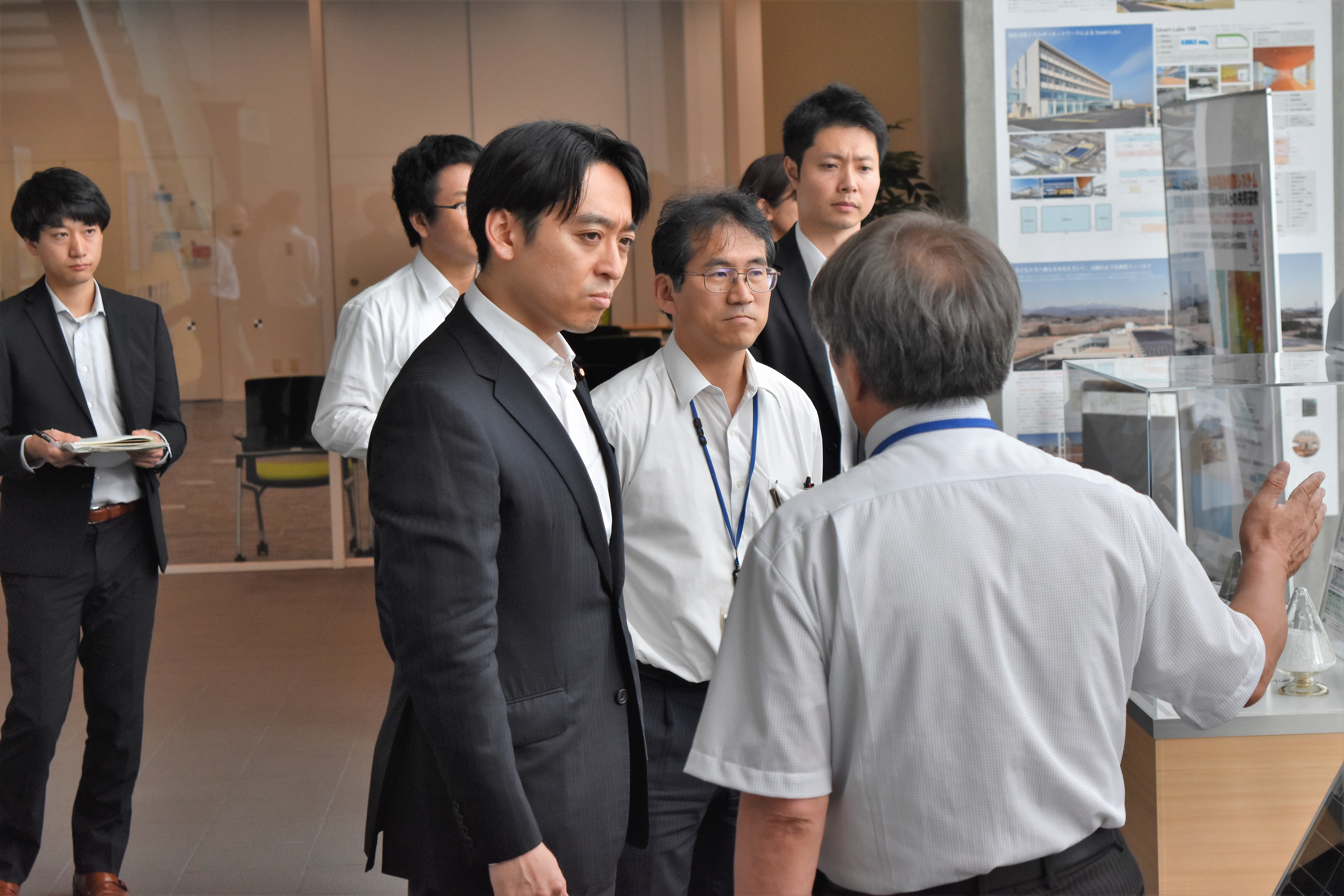 Parliamentary Vice-Minister Hiraki (center) listening to an explanation of a product developed by a local company.