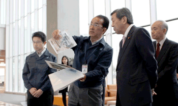 (株)山王担当者（左二名）によるシーズ支援プログラムの実施テーマの説明をお聞きになる林大臣（右から２番目）の写真