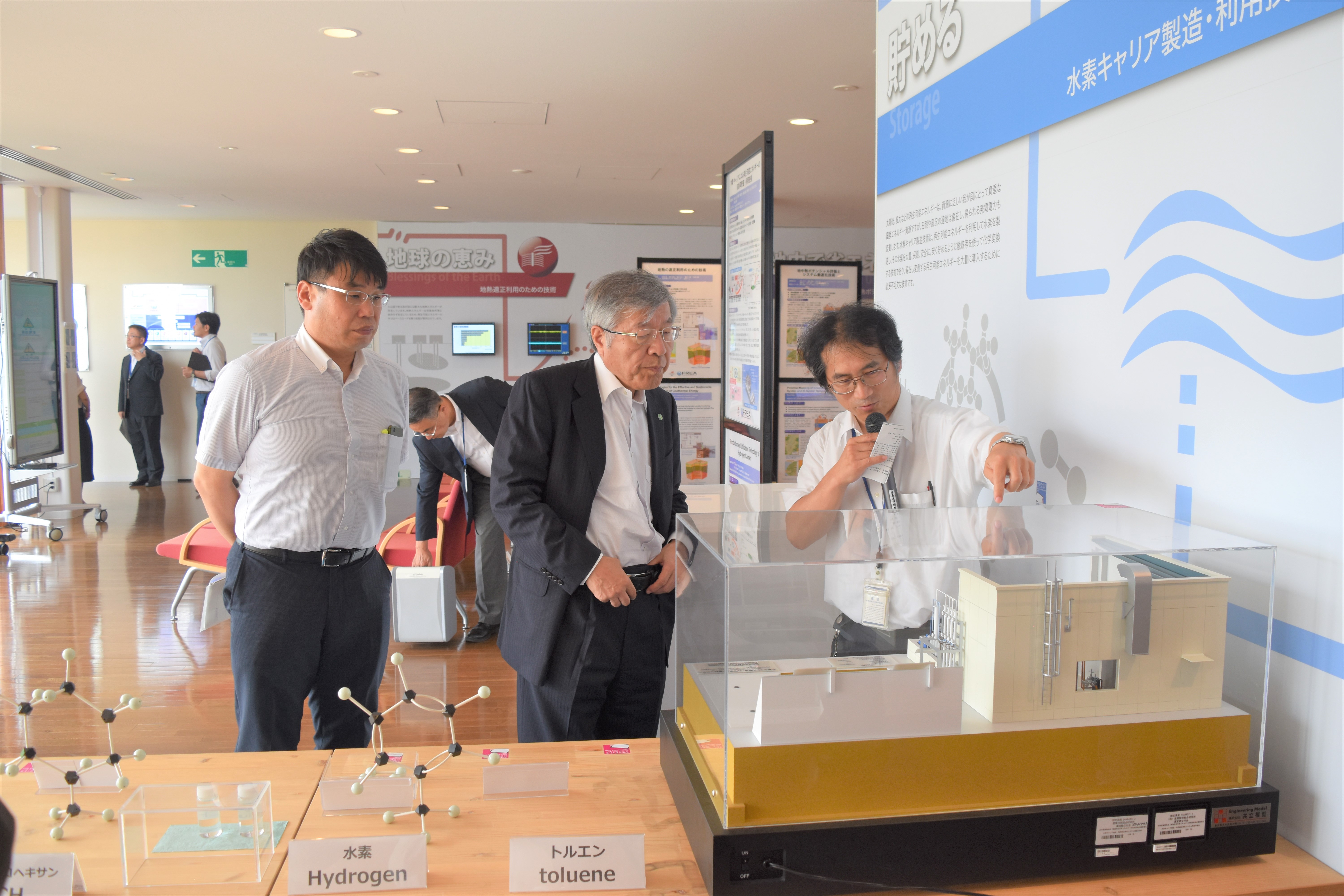 President Kazuo Kyuma (center) listening to an explanation in the Energy Control Building.