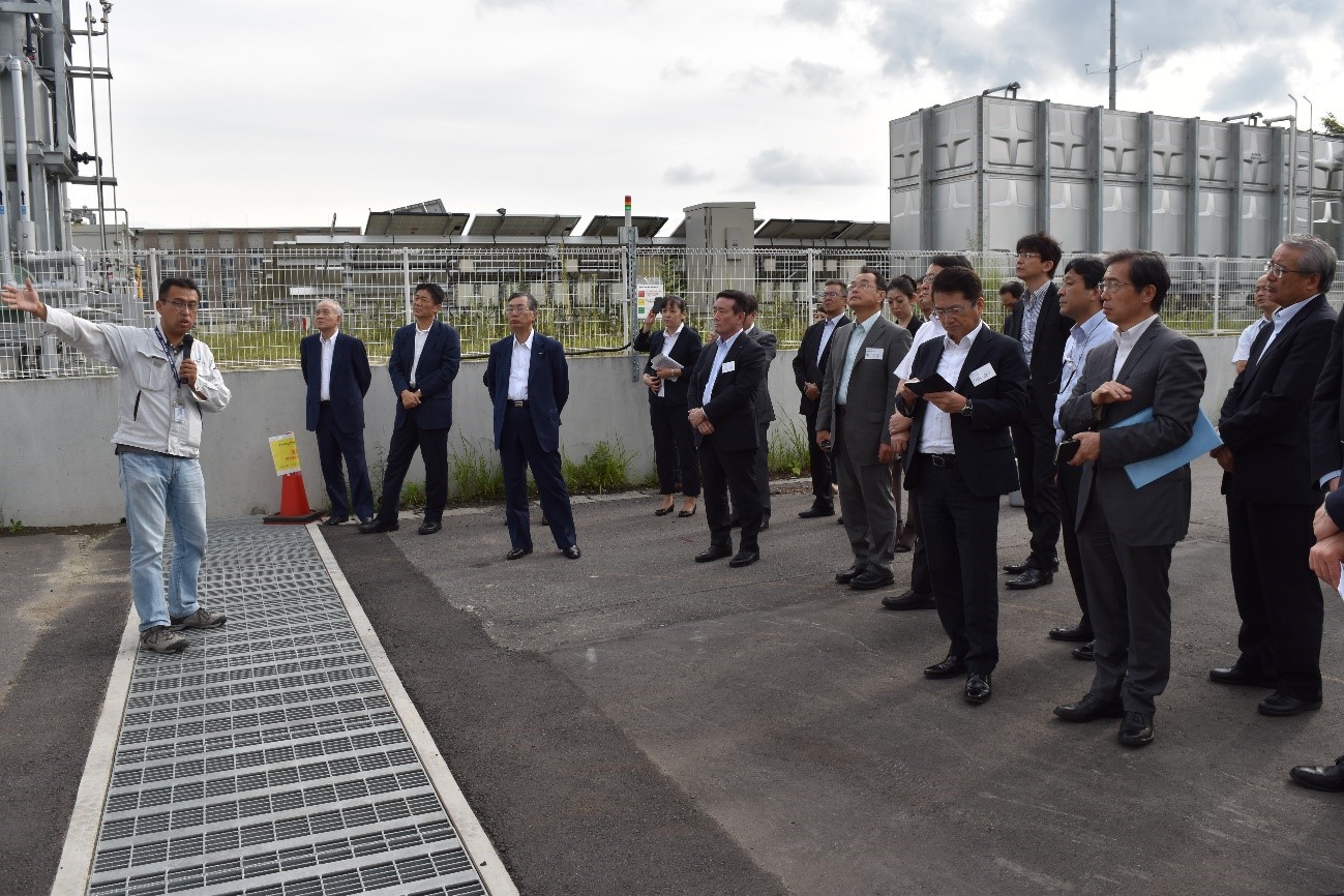 Keidanren members listening to an explaining by a researcher, Mr. Namba, in the Outdoor Demonstration Field.