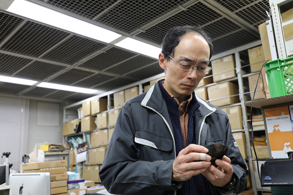 採取された岩石を手にする石塚さんの写真