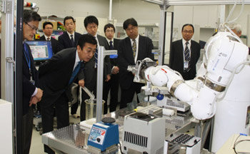 ライフサイエンス実験ロボット「まほろ」の実演をご覧になる星野政務官(左)の写真