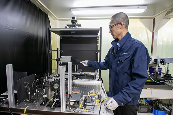 開発した検査装置と坂田の写真