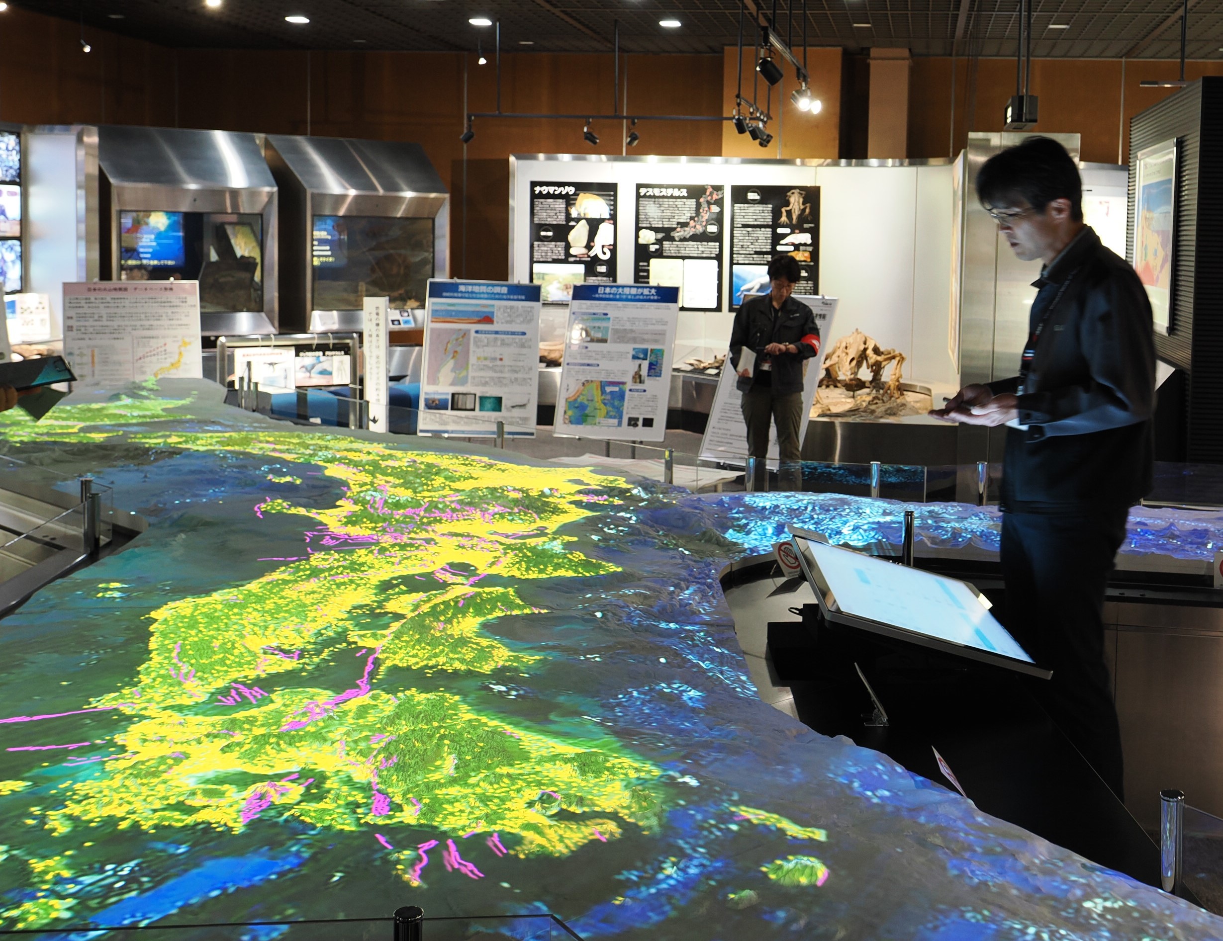 地質標本館の日本列島大型3Dプロジェクションマッピングを使って説明する地質情報研究部門 野田篤研究部門長