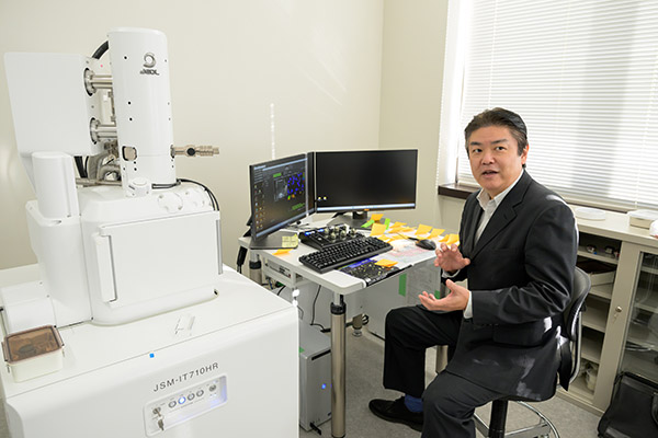 分析装置の前で話す大木さん