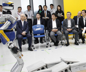 ヒューマノイドロボットの実演をご覧になる鶴保大臣（中央）の写真