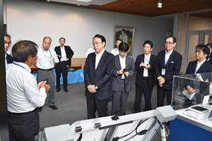 地元企業が開発中の試作品説明をお聞きになる長沢復興副大臣(中央)の写真