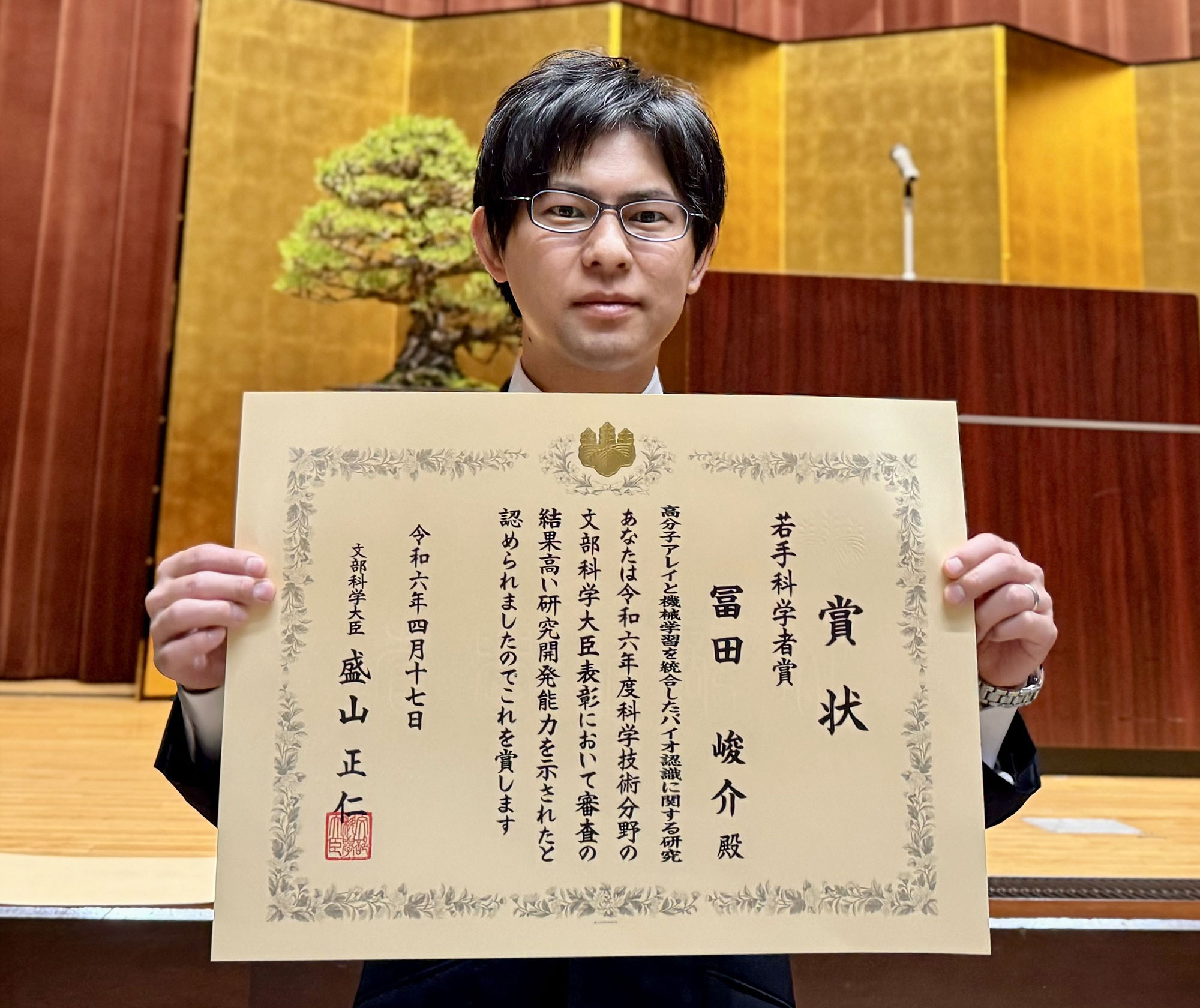 賞状を持つ冨田峻介上級主任研究員写真
