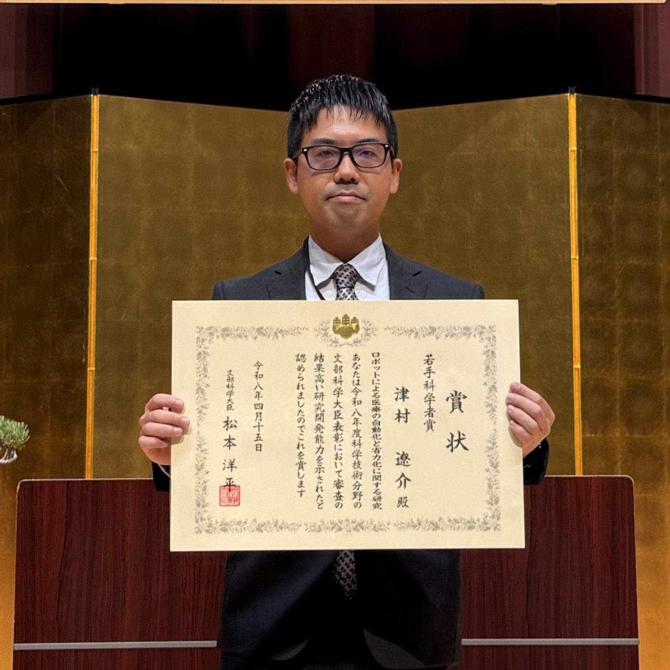 賞状を持つ津村遼介産業技術企画調査員写真