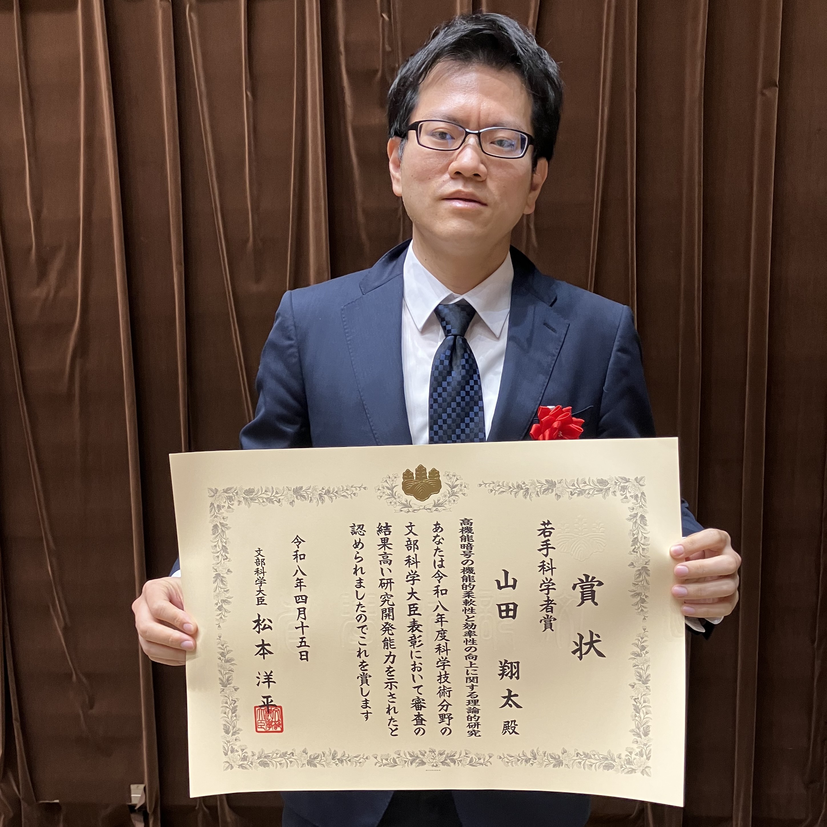 賞状を持つ山田翔太上級主任研究員写真