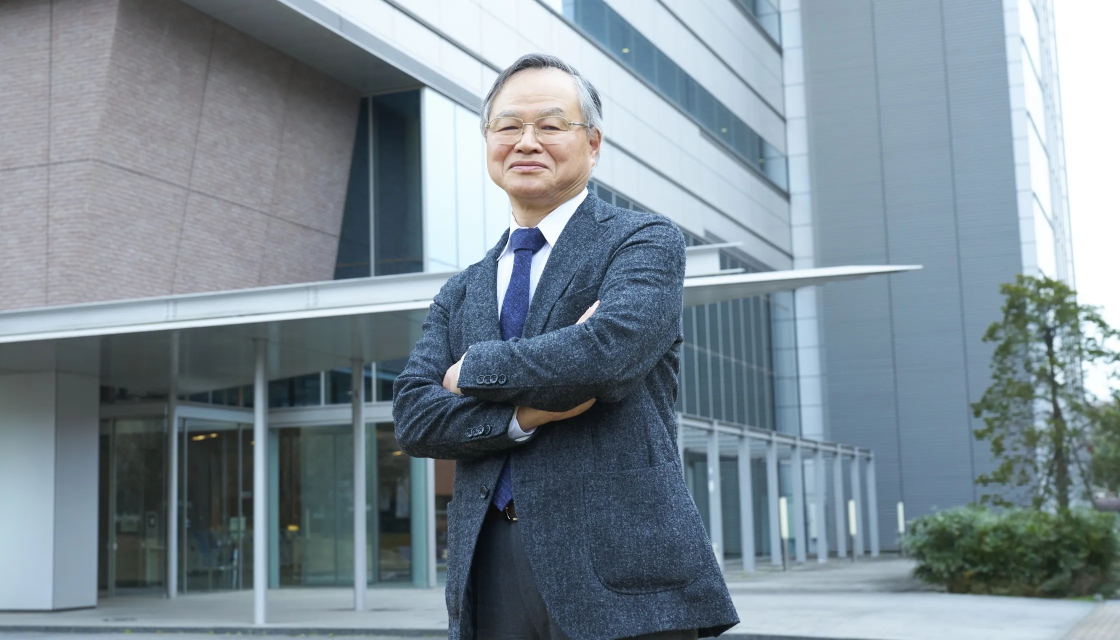研究所の入り口の前で腕を組んで立っている一村信吾さん