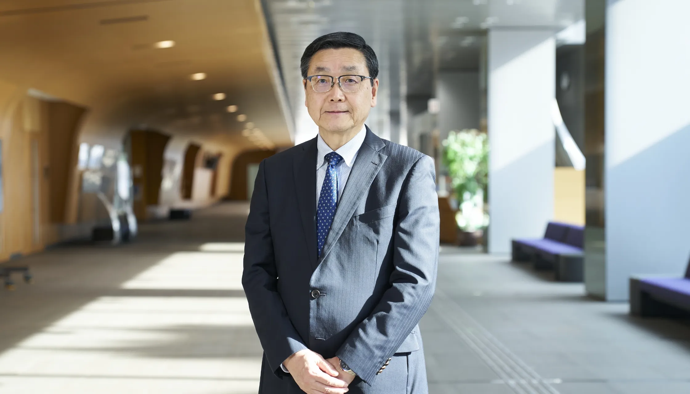 室内の広い空間を背に直立している村山宣光さん