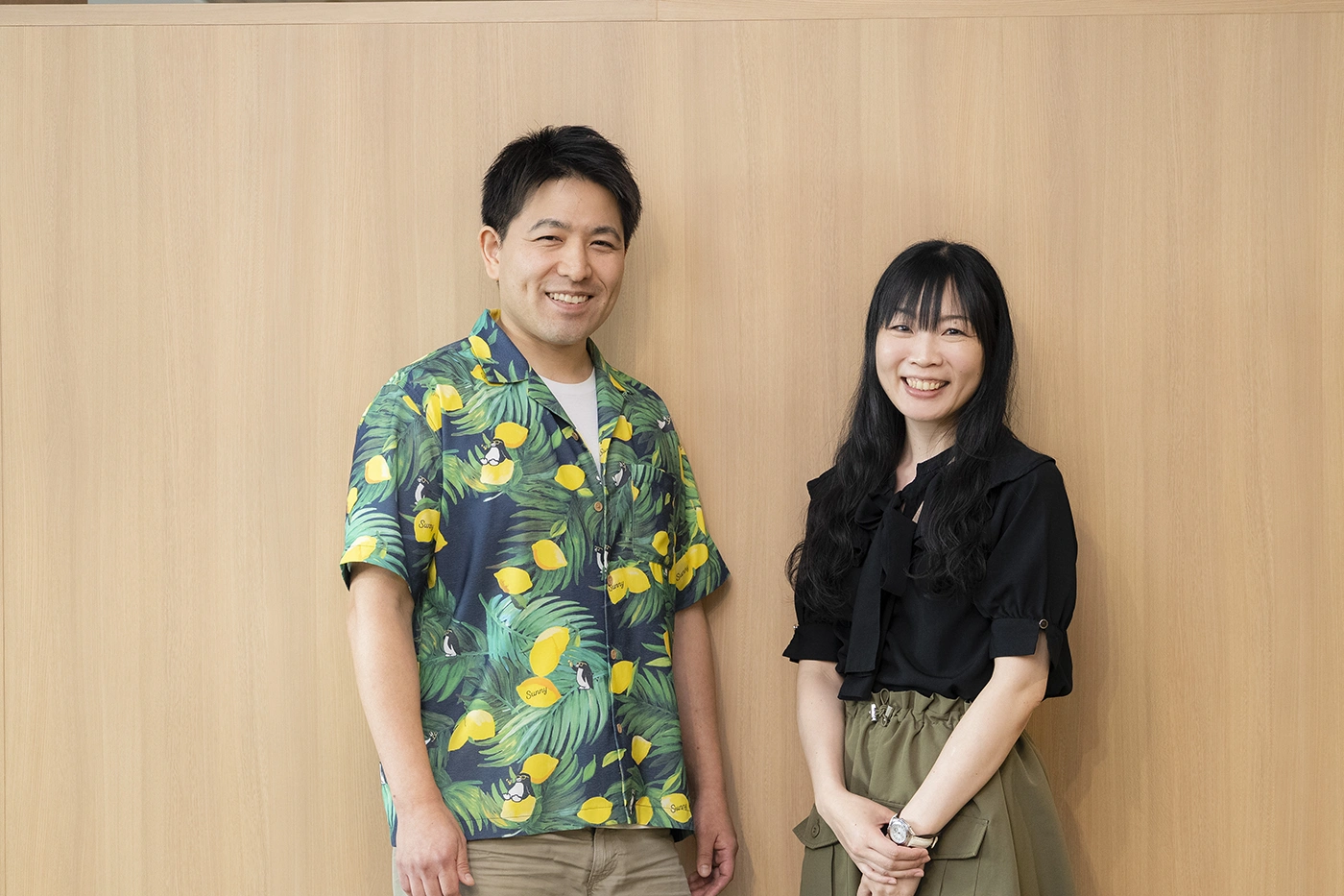 木目の壁の前で並び、にこやかな笑顔を見せる馬場宗明（左）と佐藤純子（右）